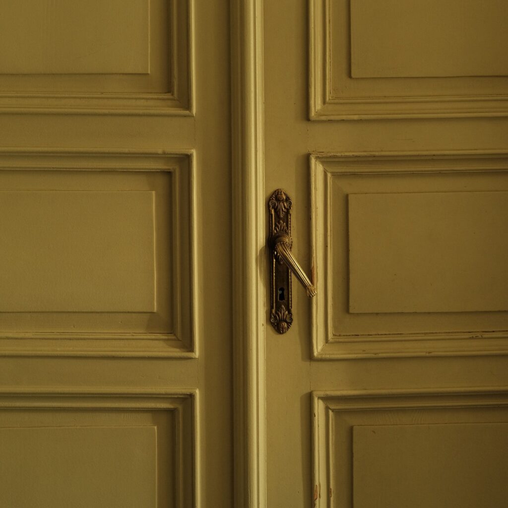 Zbliżenie klasycznych drewnianych drzwi z ozdobnym vintage uchwytem, podkreślające eleganckie rzemiosło
